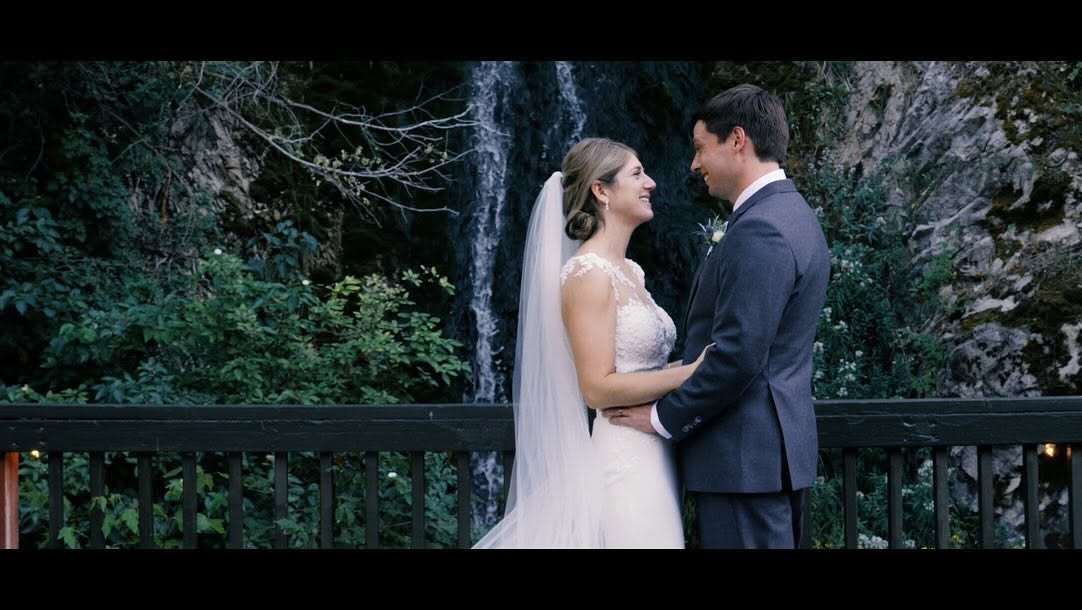 Newlyweds standing together in front of a waterfall