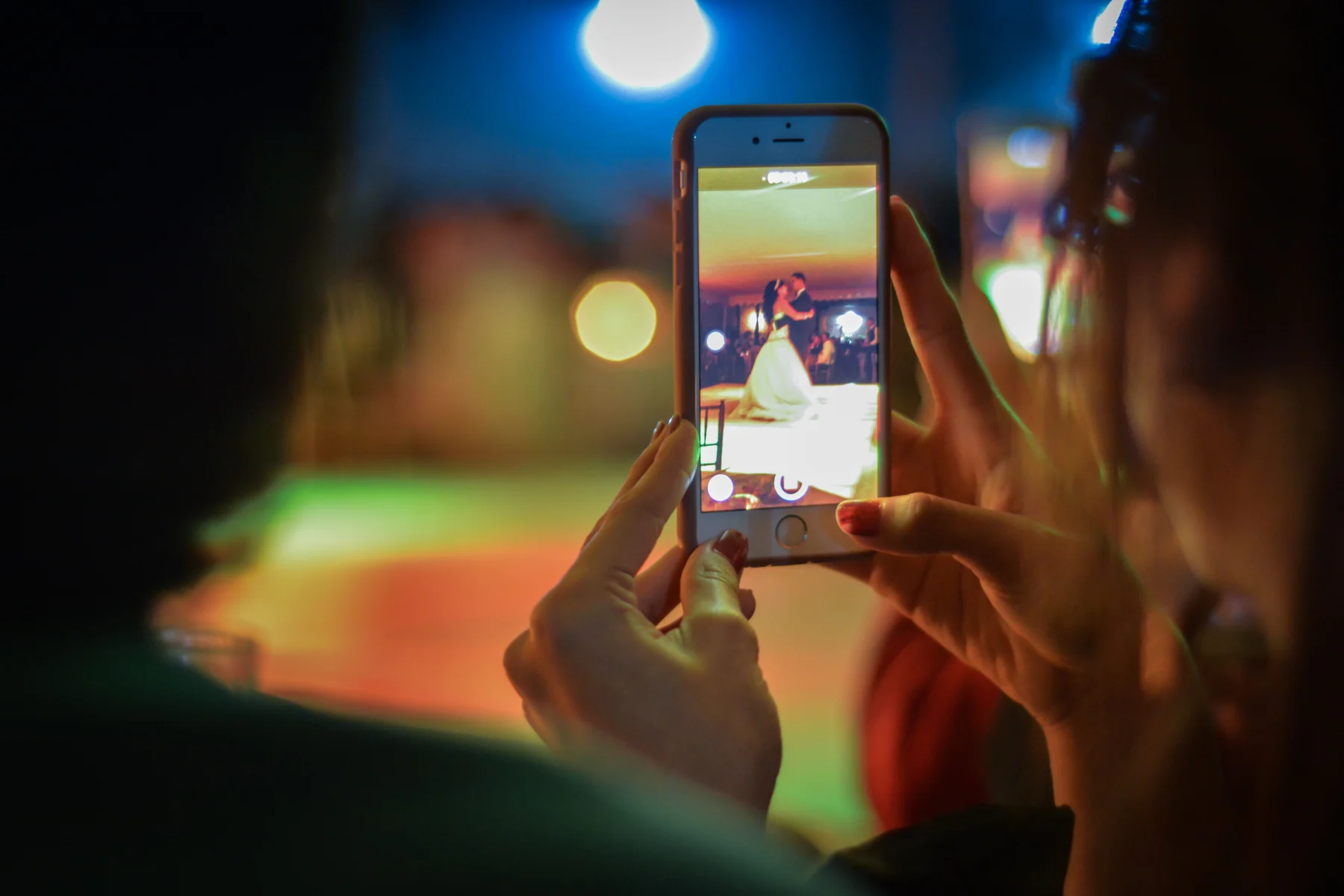 A wedding guest filming the newlyweds on a phone